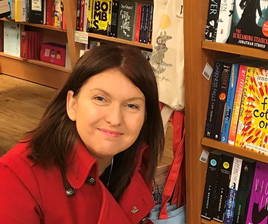 Image of a white woman in a red coat in a bookshop