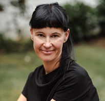 Image of a white woman with black hair and a black top outside