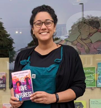 Image of a Black woman in dungarees holding a book