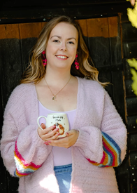 Image of a white woman in a pink cardigan holding a cup