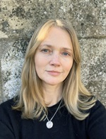 Image of a white woman with white hair against a grey stone wall