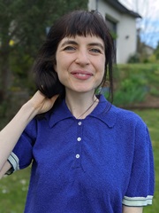 Image of a white woman with black hair in a blue top outside