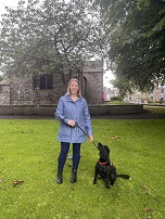 Image of a white woman with a dog on a green