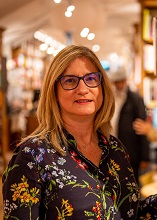 Image of a white woman with blonde hair against a blurred sookshop