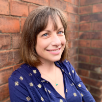Headshot of a woman white woman against a brick wall