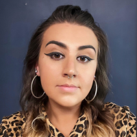 Headshot of a white woman with loop earrings and a leopard print shirt
