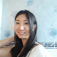 Headshot of a woman with long black hair  against blue tiles 