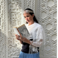 Photo of a white woman reading a book against a textured white wall