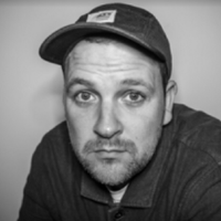 Greyscale headshot of a white man in a cap