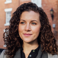 Headshot of a white woman with curly brown hair outside