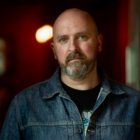 Headshot of a white man in a dark interior space