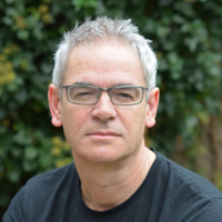 Headshot of white man against green leaves