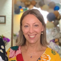 Headshot of a white woman in a yellow top inside