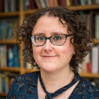 Headshot of a white woman with short curly hair before bookcase