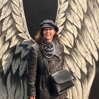 Photo of a woman standing against street art of angel wings