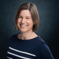 Photo of a white woman in a dark top against a dark background