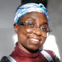 Headshot of a Black woman with a bandana around her hair and glasses