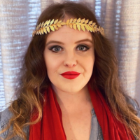 Head shot of a white woman with loose brown hair in a gold leaf circlet