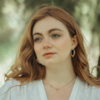 Headshot of a white woman with red hair outside