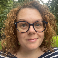 Headshot of a white woman with curly brown hair outside