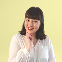 Headshot of a white woman with shoulder length brown hair against yellow