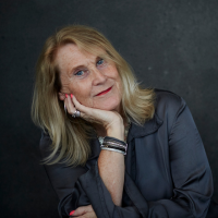 Headshot of a white woman with blonde hair with chin on hand