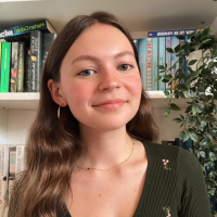 Headshot of a white woman with long brown hair in front of bookshelves