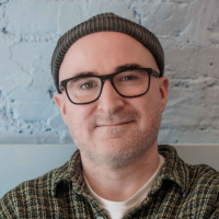 Headshot of a white man in a beanie with glasses