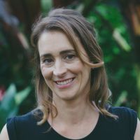 Head shot of a white woman outside before greenery