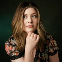 headshot of a white woman with brown hair resting her face on her hand