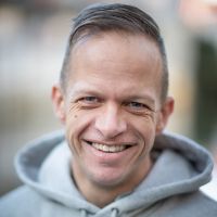 Headshot of a white man in a hoodie outside