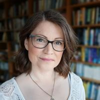 Headshot of a white woman with short brown hair against bookshelves