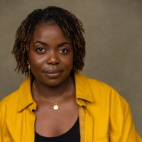 Headshot of a Black woman leaning to one side in a yellow top