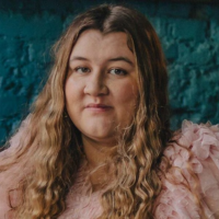 Headshot of a white woman with light brown hair and a pink top